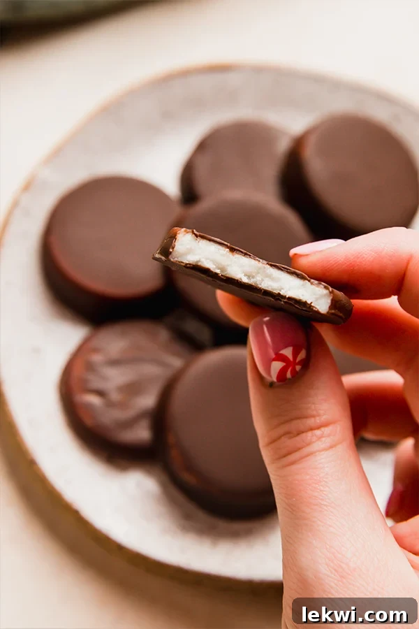 Person holding a halved homemade peppermint patty over a plate of patties.