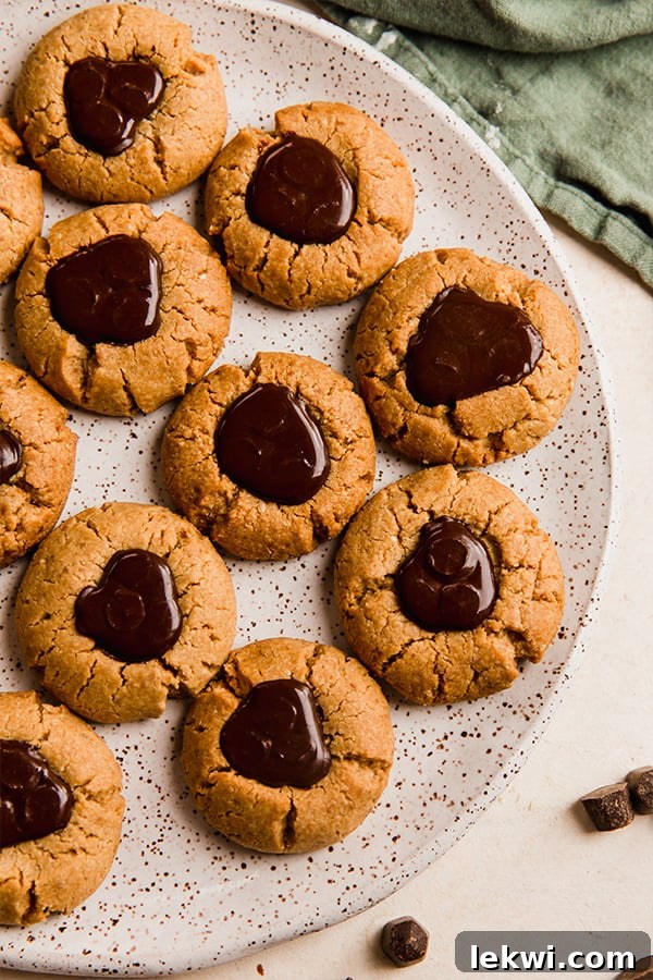Plate of perfectly baked almond butter blossoms, garnished with a chocolate kiss-like topping.