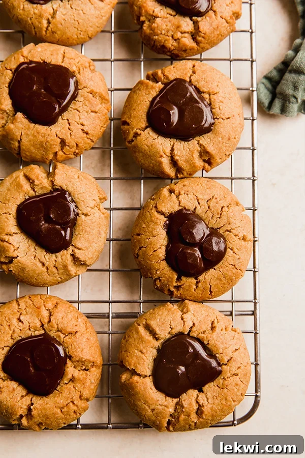 Warm almond butter blossoms cooling on a rack, each with melted chocolate in the center.