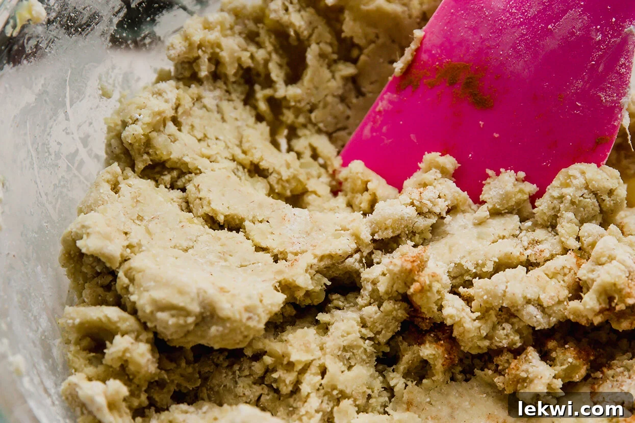 Gingerbread cinnamon roll dough mixed in a bowl with a spoon, showing its texture.