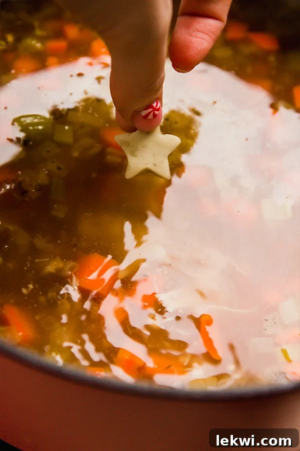 A steaming bowl of gluten-free chicken and stars soup, garnished with fresh herbs, ready to be served.
