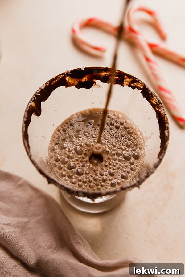 Peppermint mocktail pouring into a glass with a chocolate rim.