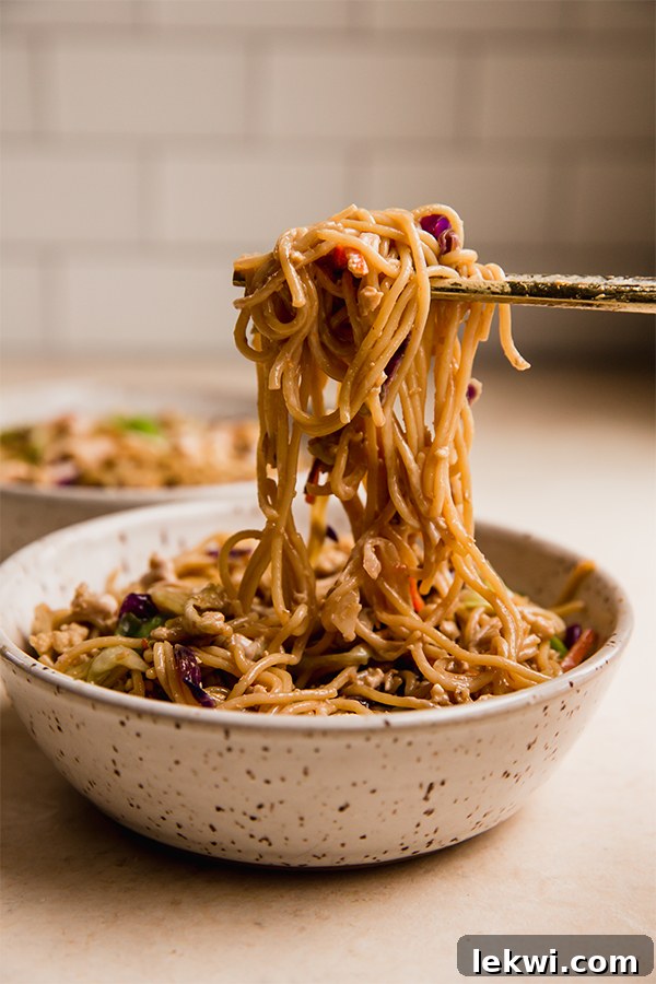 A bowl of egg roll ramen with chopsticks grabbing a portion of noodles and vegetables.