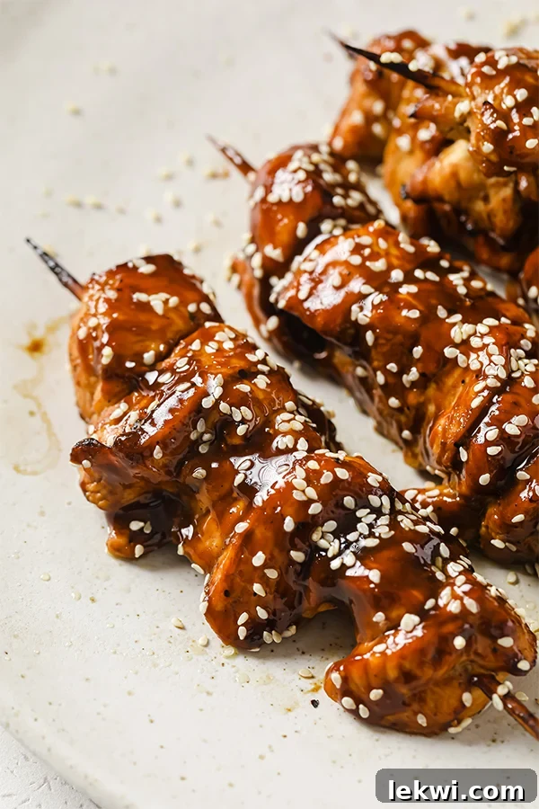 A plate with teriyaki chicken skewers on it