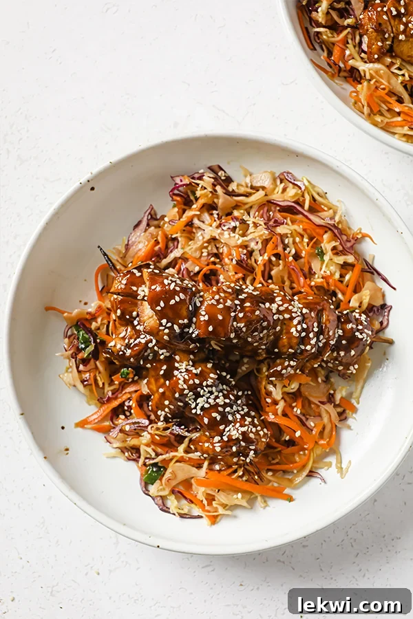A bowl with asian-inspired slaw and teriyaki chicken skewers