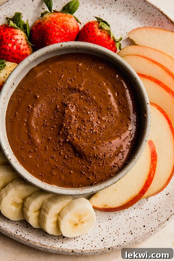 A beautifully arranged selection of fresh fruits surrounding a bowl of creamy chocolate fruit dip, ready to be enjoyed as a healthy snack or dessert.