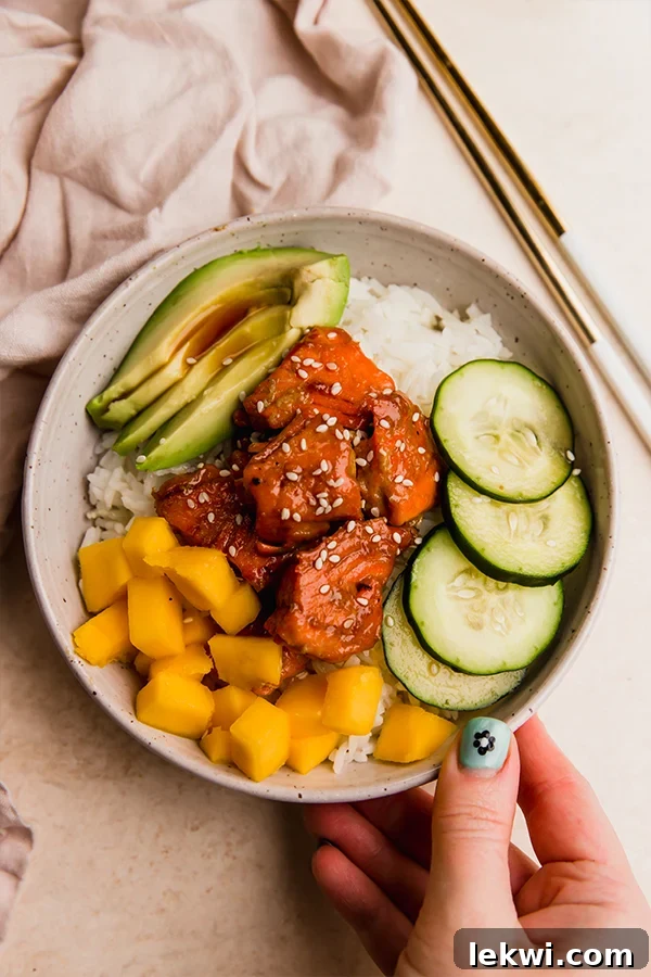 Garlic ginger salmon in a bowl with rice, vegetables, and mango.