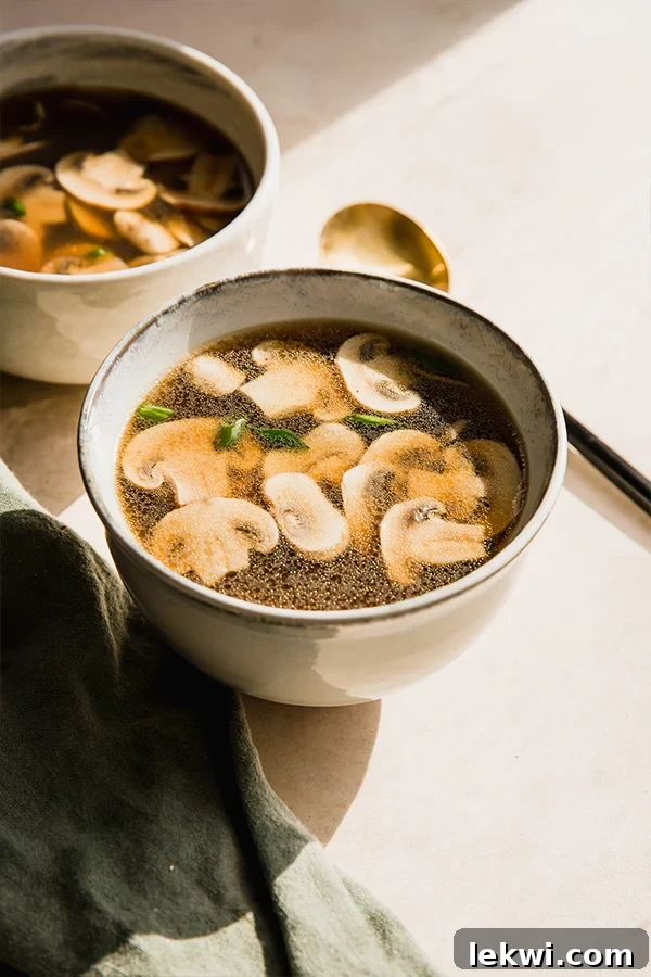 A close-up shot of a bowl of Japanese clear soup, showing the clear broth and sliced mushrooms.