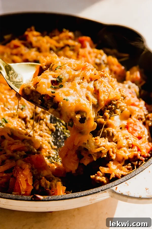 Scoop scooping dairy-free "cheesy" beef and sweet potato skillet from a pan.
