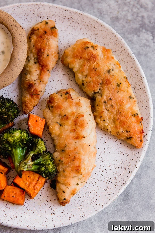 Golden brown crispy chicken tenders served on a plate with perfectly roasted sweet potatoes and broccoli florets.