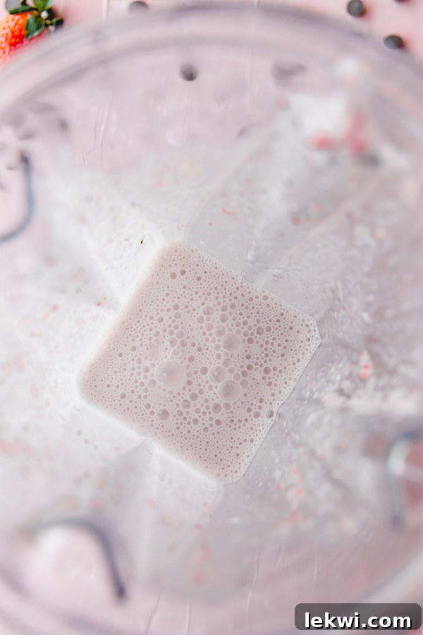 A creamy strawberry mocktail mixture swirling smoothly inside a blender, ready for the next step.