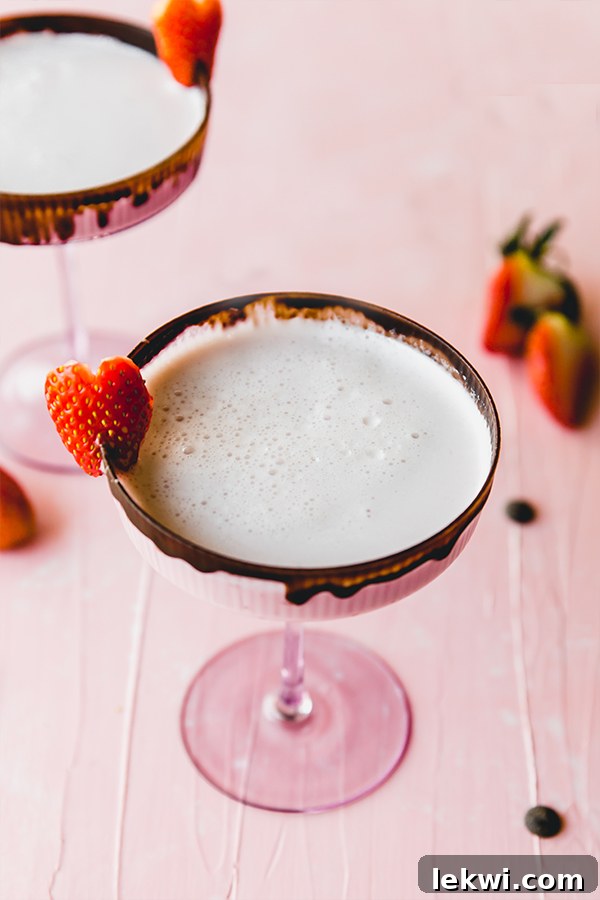 A beautifully presented chocolate covered strawberry mocktail, garnished with fresh fruit, sitting elegantly on a rustic wooden table.