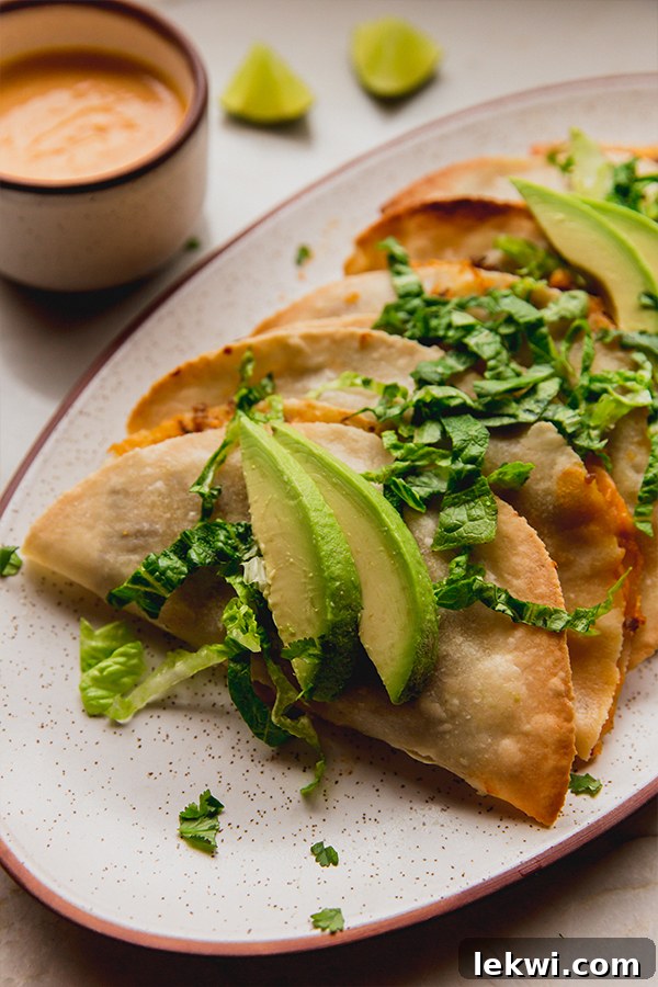 A close-up shot of crispy baked ground beef tacos adorned with fresh avocados and crisp romaine lettuce.