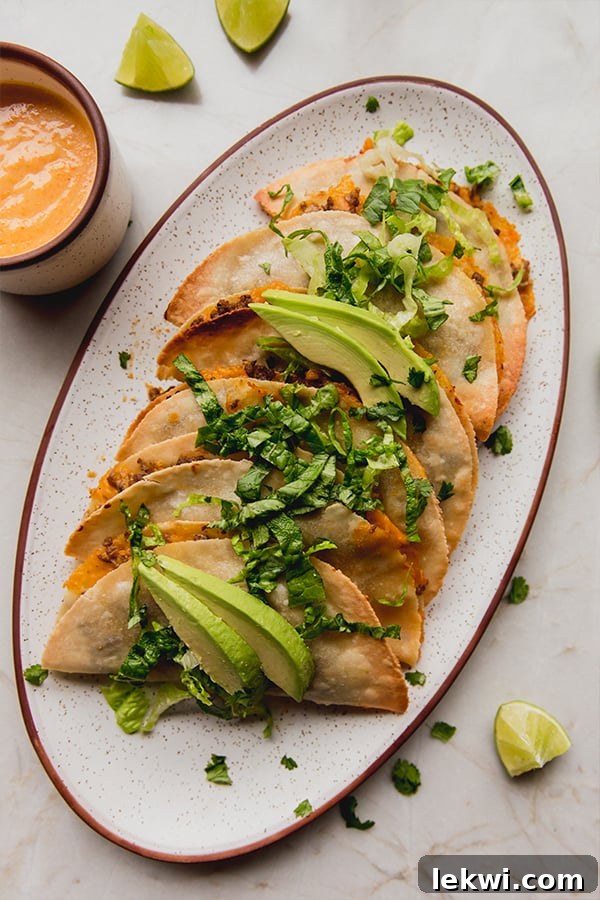 Baked ground beef tacos on a platter topped with avocado.