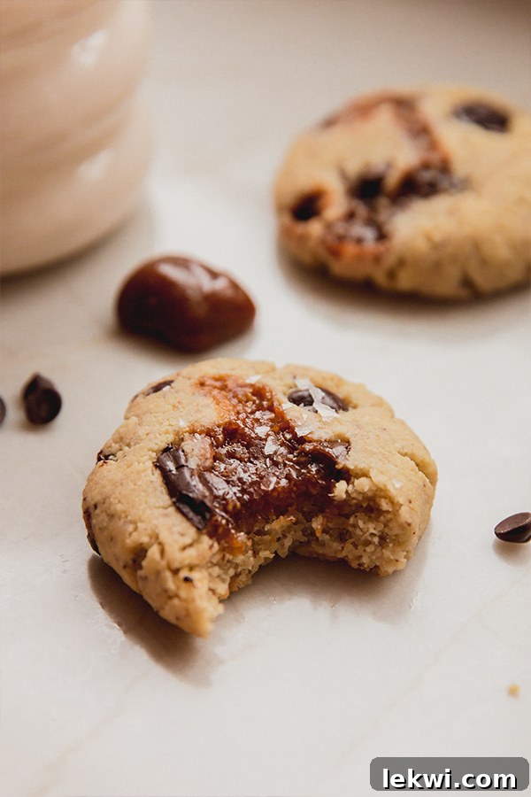 A chocolate chip caramel cookie with a bite taken out of it, showing the gooey caramel center.
