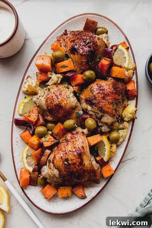 A beautifully arranged platter of Sheet Pan Mediterranean Chicken and Roasted Vegetables, garnished with fresh herbs and a drizzle of creamy sauce.