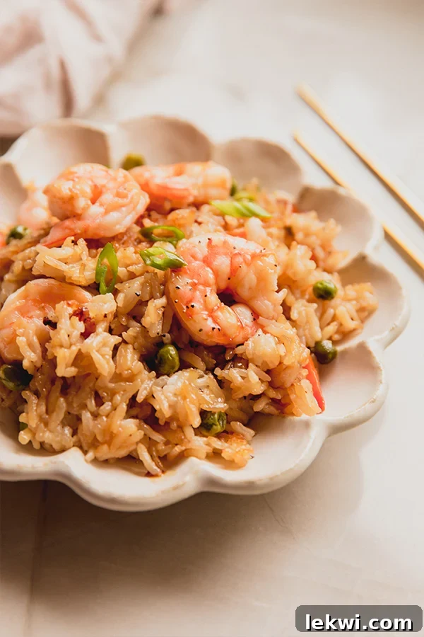 A vibrant bowl of sheet pan shrimp fried rice, showcasing perfectly crispy edges and fresh scallions.