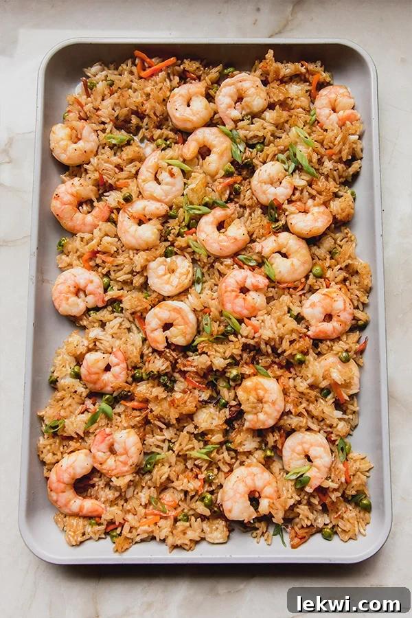 A large sheet pan filled with freshly cooked shrimp fried rice, showcasing the vibrant colors and crispy texture.