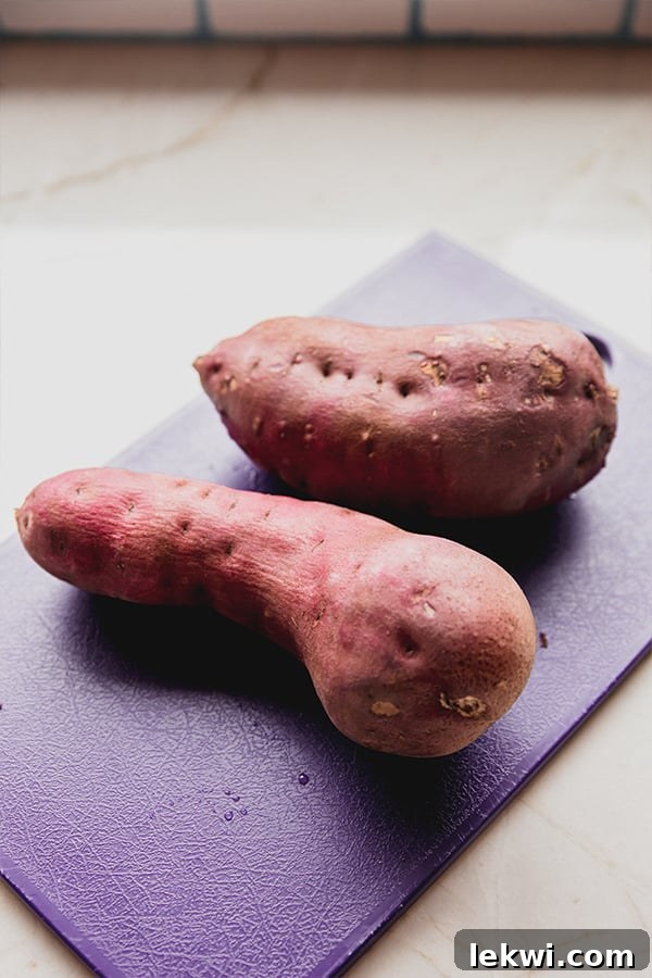 Close-up shot of Japanese white sweet potatoes on a wooden cutting board, highlighting their purple skin and potential for delicious meals.