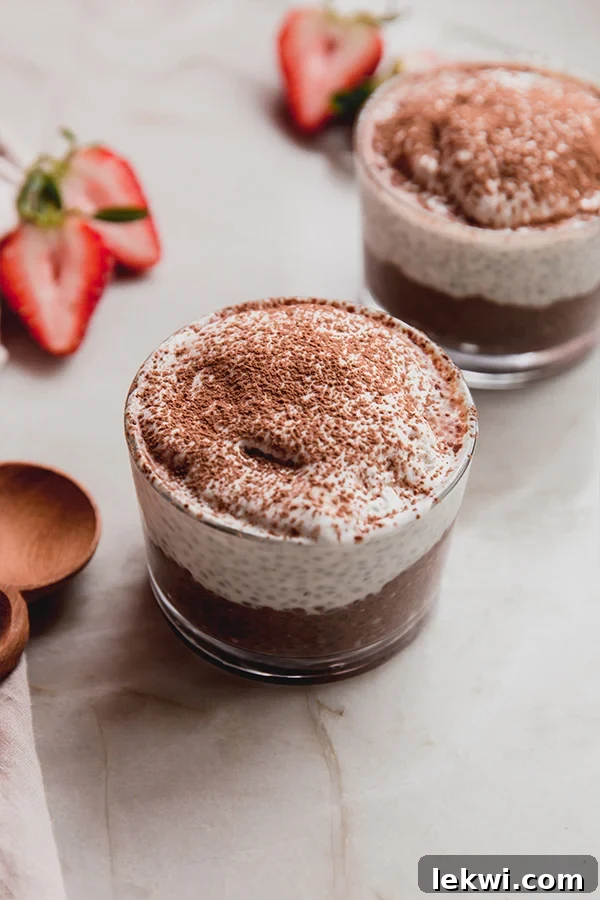 Two small glasses of tiramisu chia pudding, garnished with a dusting of cocoa powder, presented side by side.