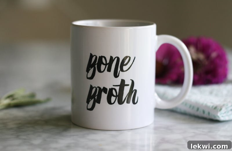 A white mug with text on it saying Bone Broth, symbolizing warmth and health.