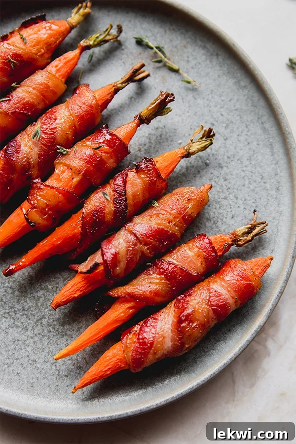 A plate of perfectly cooked bacon-wrapped carrots, glistening with a maple balsamic glaze.