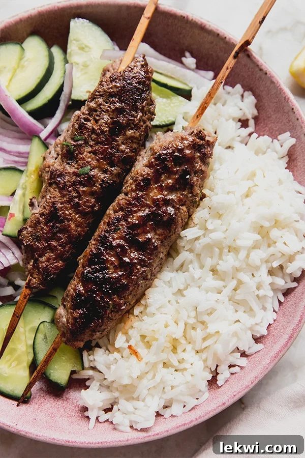 Two beef kofta skewers served over rice and mixed vegetables.