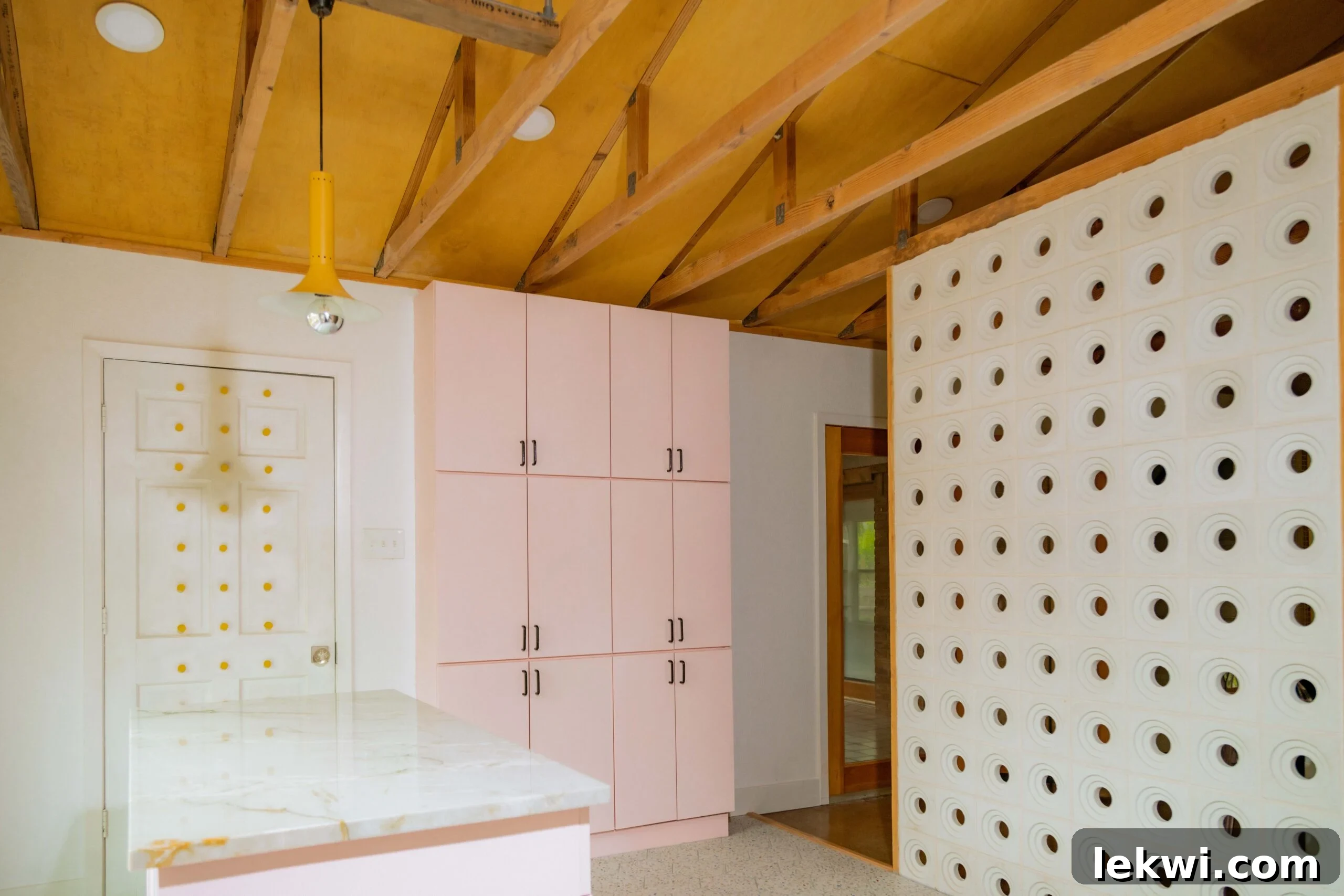 After renovation: A section of pink kitchen cupboards installed against a wall, showcasing the chosen color palette and cabinet style.