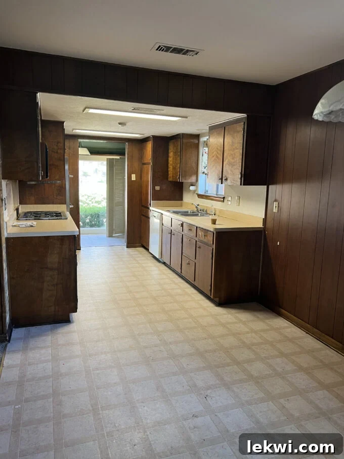 Before renovation: Close-up of old tile floor in a kitchen with dark brown cabinets, highlighting the dated appearance.