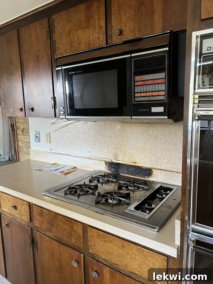 Before renovation: Microwave installed over a stovetop, demonstrating an older kitchen appliance setup.