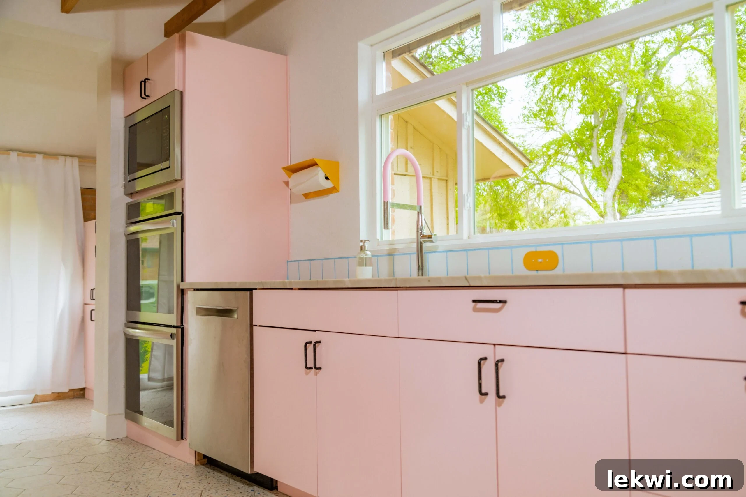 After renovation: A cheerful pink kitchen with modern appliances and a pink faucet, showcasing attention to colorful details.