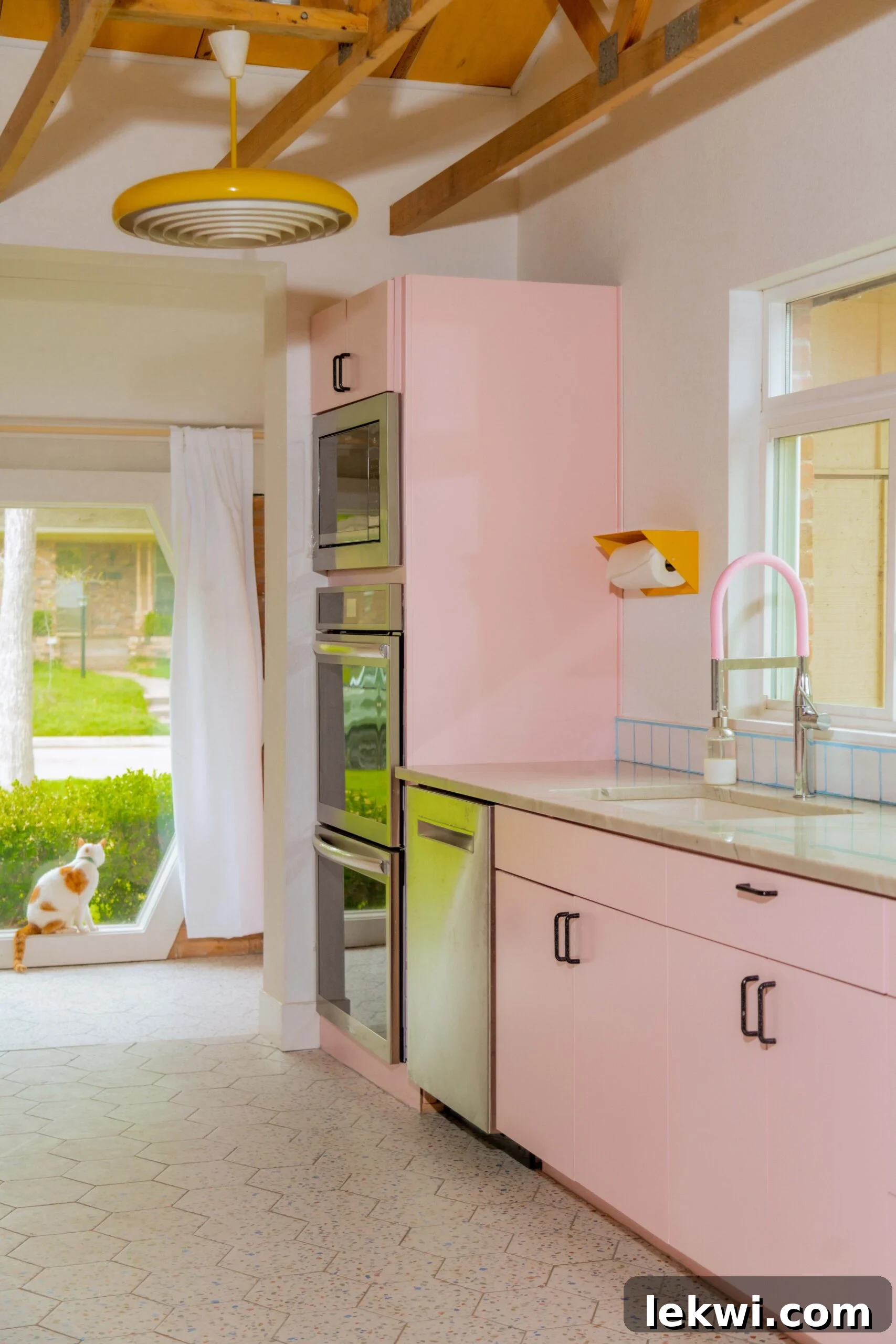 After renovation: A cat observing from a window in the charming pink kitchen, highlighting the cozy and personalized atmosphere.
