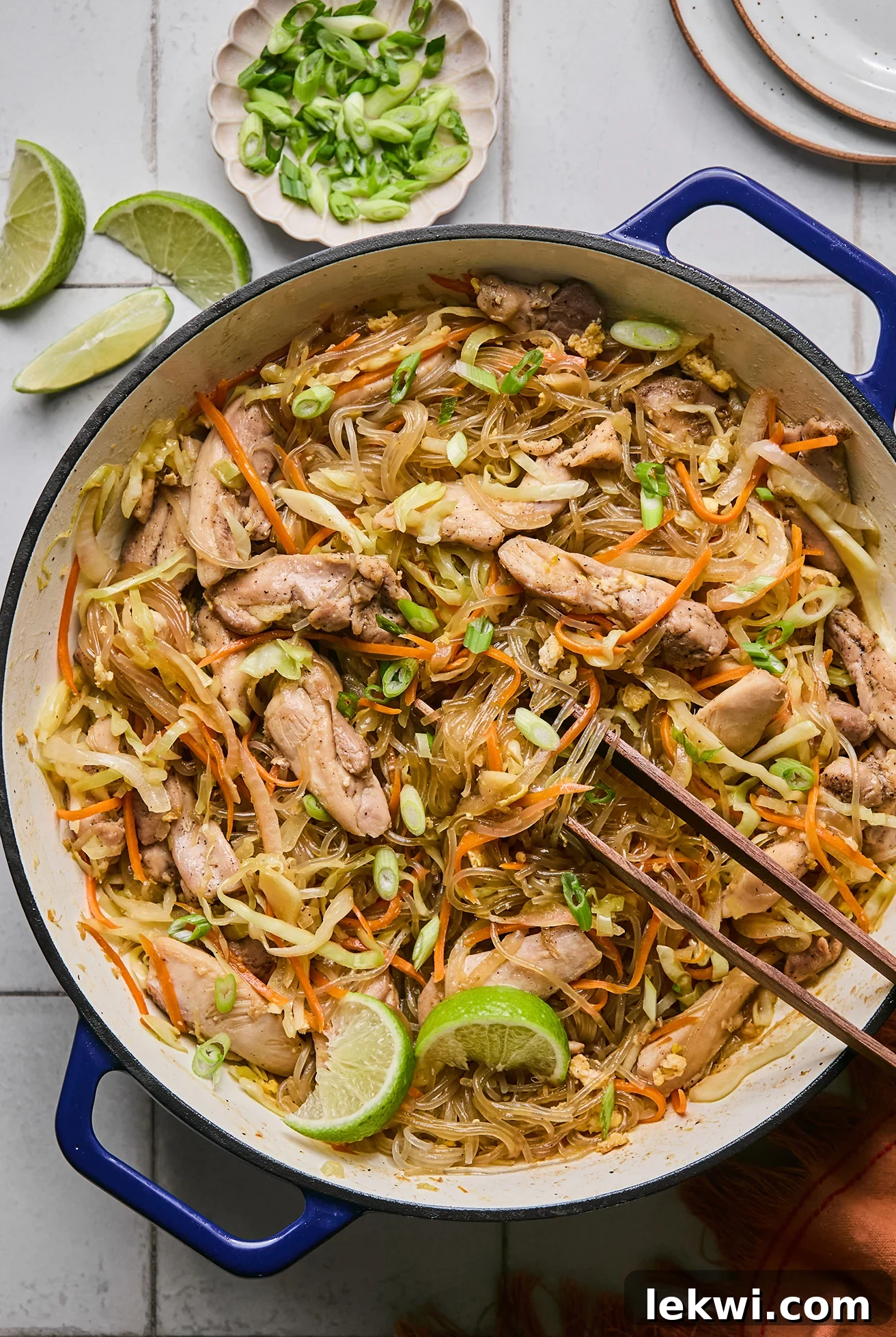 Pad woon sen in a large cast iron pan topped with limes.