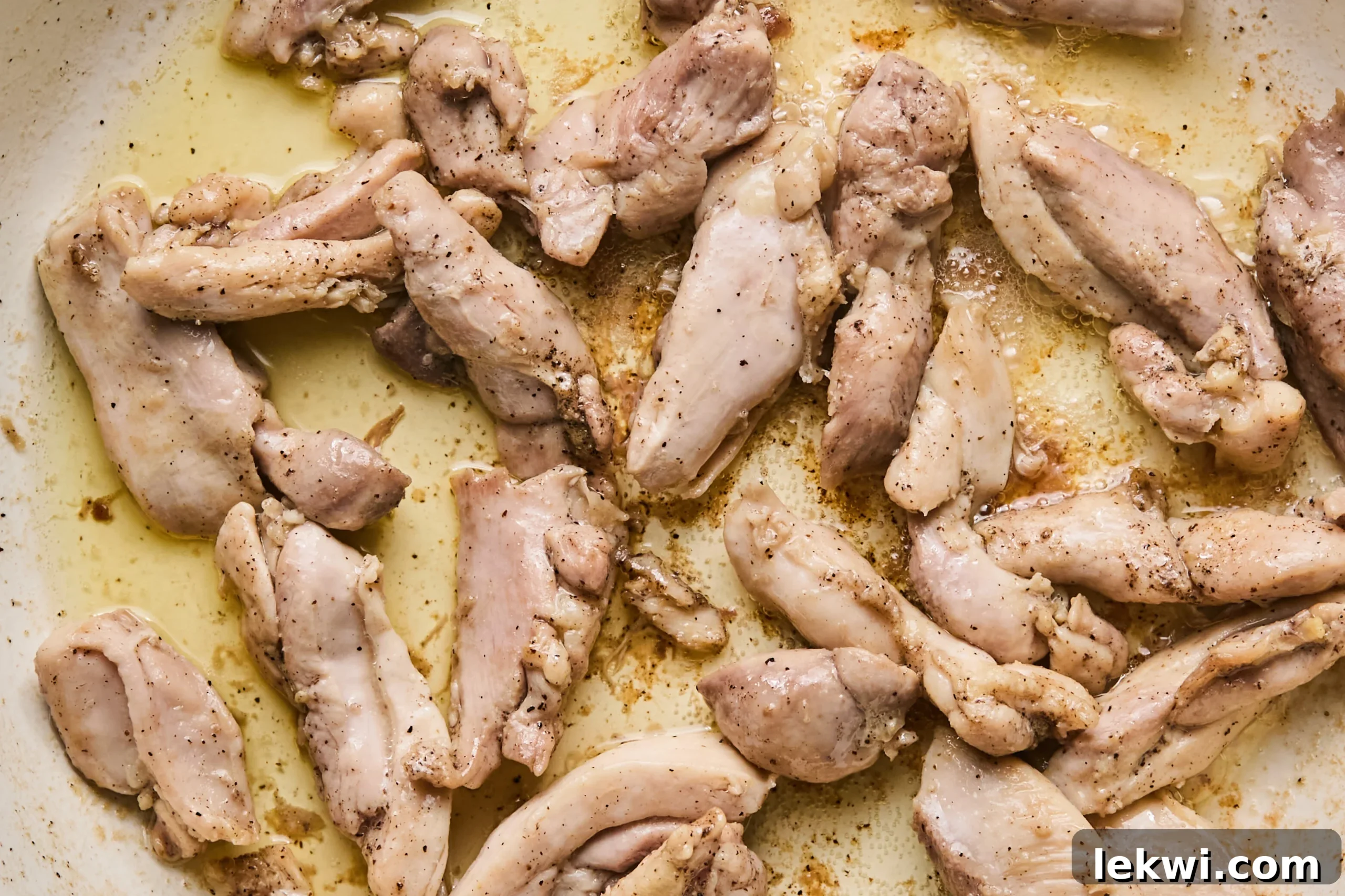 Sliced chicken thighs, perfectly cooked and browned, resting in a pan, ready to be set aside.