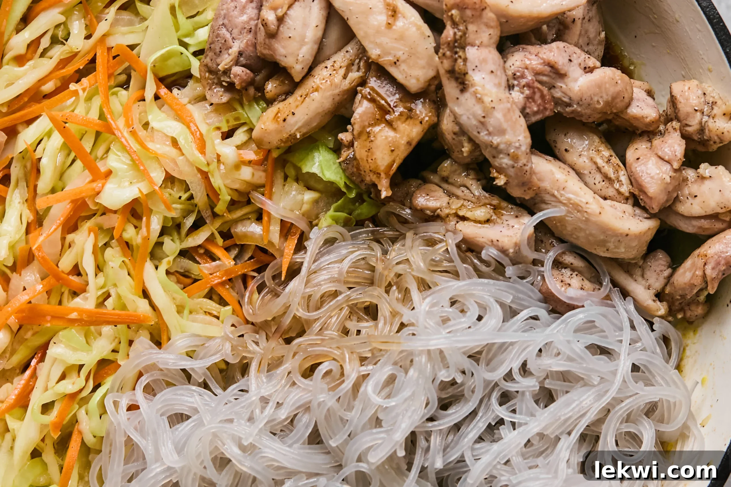 All the stir fry components – cooked chicken, tender vegetables, and softened glass noodles – combined in a pan, awaiting the final sauce coating.