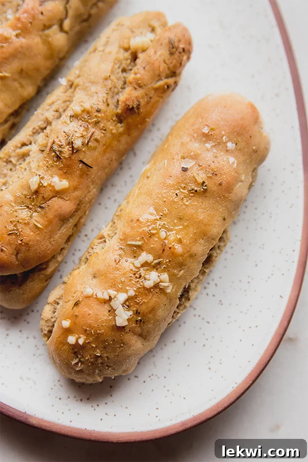 Plate of golden-brown gluten-free Italian breadsticks, perfectly baked and ready to be served, highlighting their inviting texture and rich color.