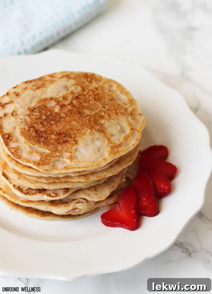 Paleo pancakes on a plate with strawberry slices.