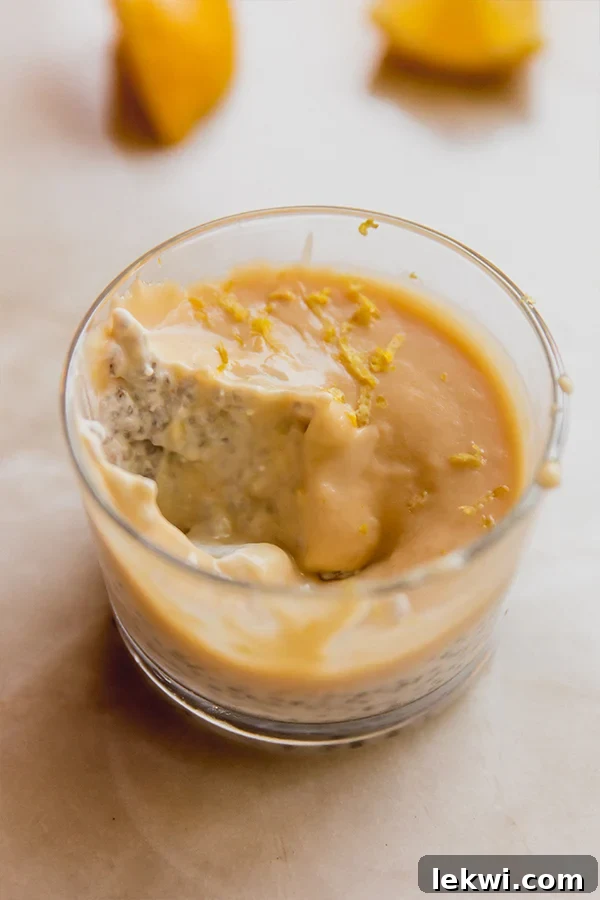 A cup of creamy lemon chia pudding with a spoonful removed, showing the two distinct layers.