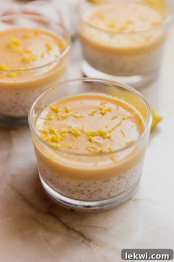 Several cups of creamy lemon chia pudding on a counter, garnished with lemon zest.