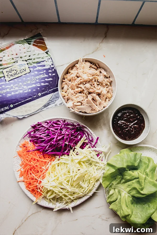 All the fresh ingredients for homemade chicken and vegetable summer rolls laid out on a kitchen counter, showcasing vibrant colors and textures.