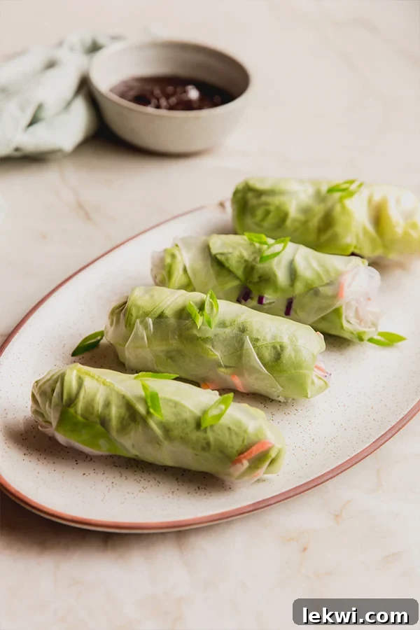 A vibrant platter of freshly prepared chicken and vegetable summer rolls, neatly arranged and ready for serving with various dipping sauces.