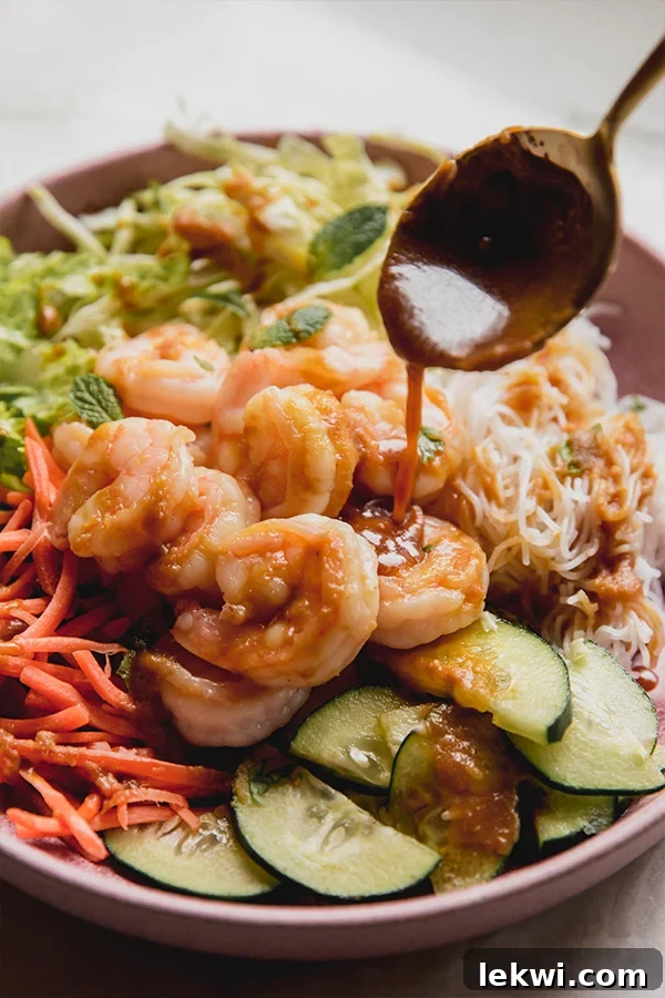 Spoon drizzling sauce over a spring roll bowl.