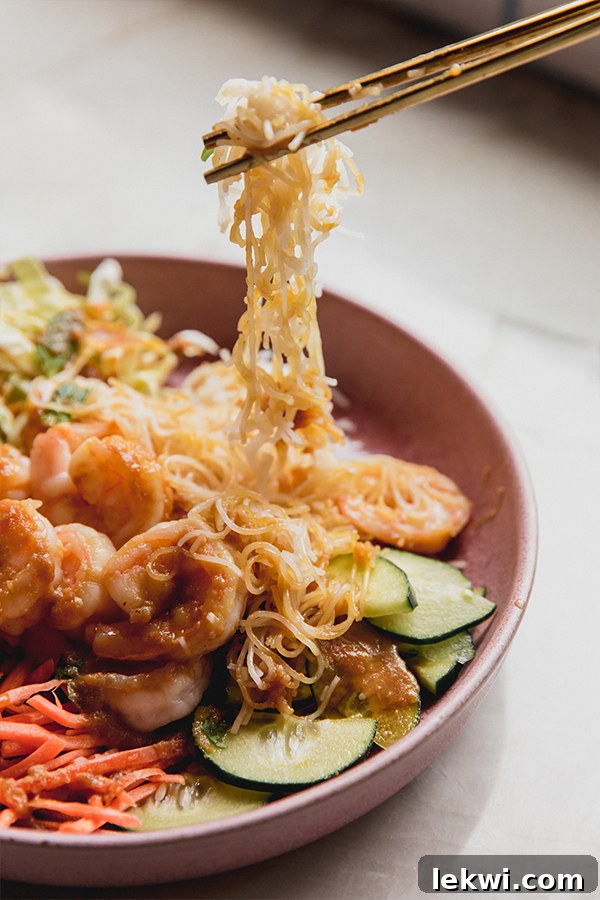Chopsticks lifting food from a spring roll bowl.