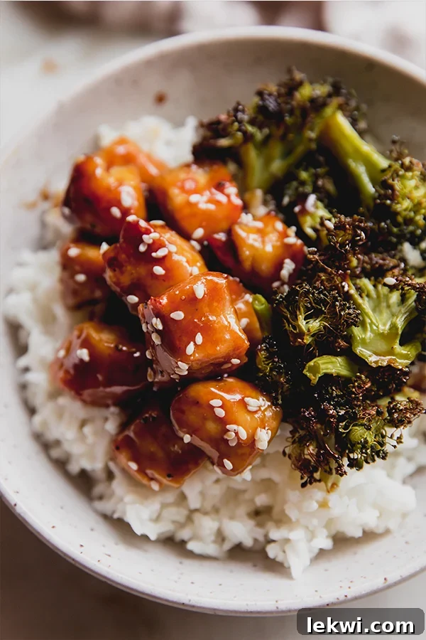 Sesame seeds on chicken in a bowl with broccoli and rice.