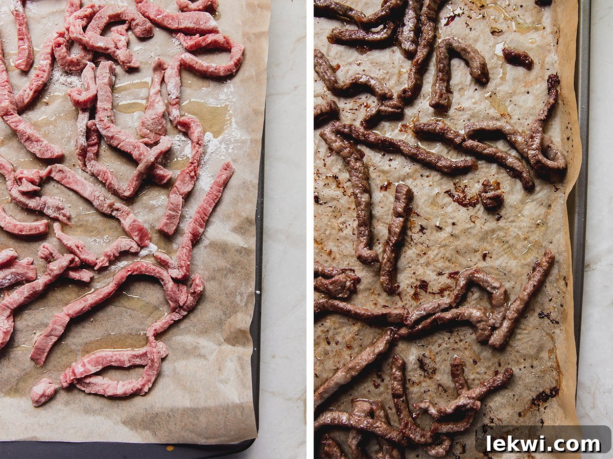 Thinly sliced flank steak, seasoned and coated with arrowroot starch, arranged in a single layer on a parchment-lined baking sheet, ready for roasting.