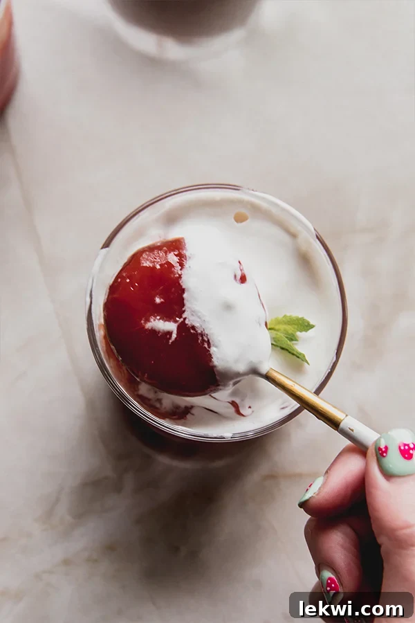A spoon scooping a bite of vibrant red Sicilian watermelon pudding, showing its smooth texture.