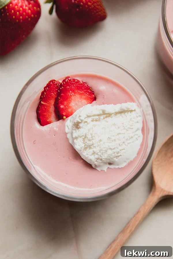 Strawberry slices elegantly arranged on a bowl of rich, dairy-free strawberries and cream pudding, inviting a delightful tasting experience.