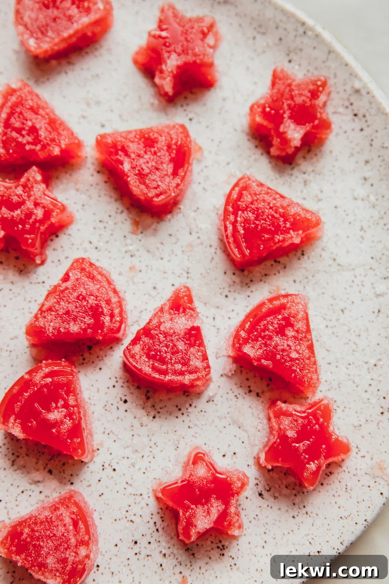 Vibrant red watermelon gummies artfully arranged on a pristine white plate, showcasing their inviting texture.