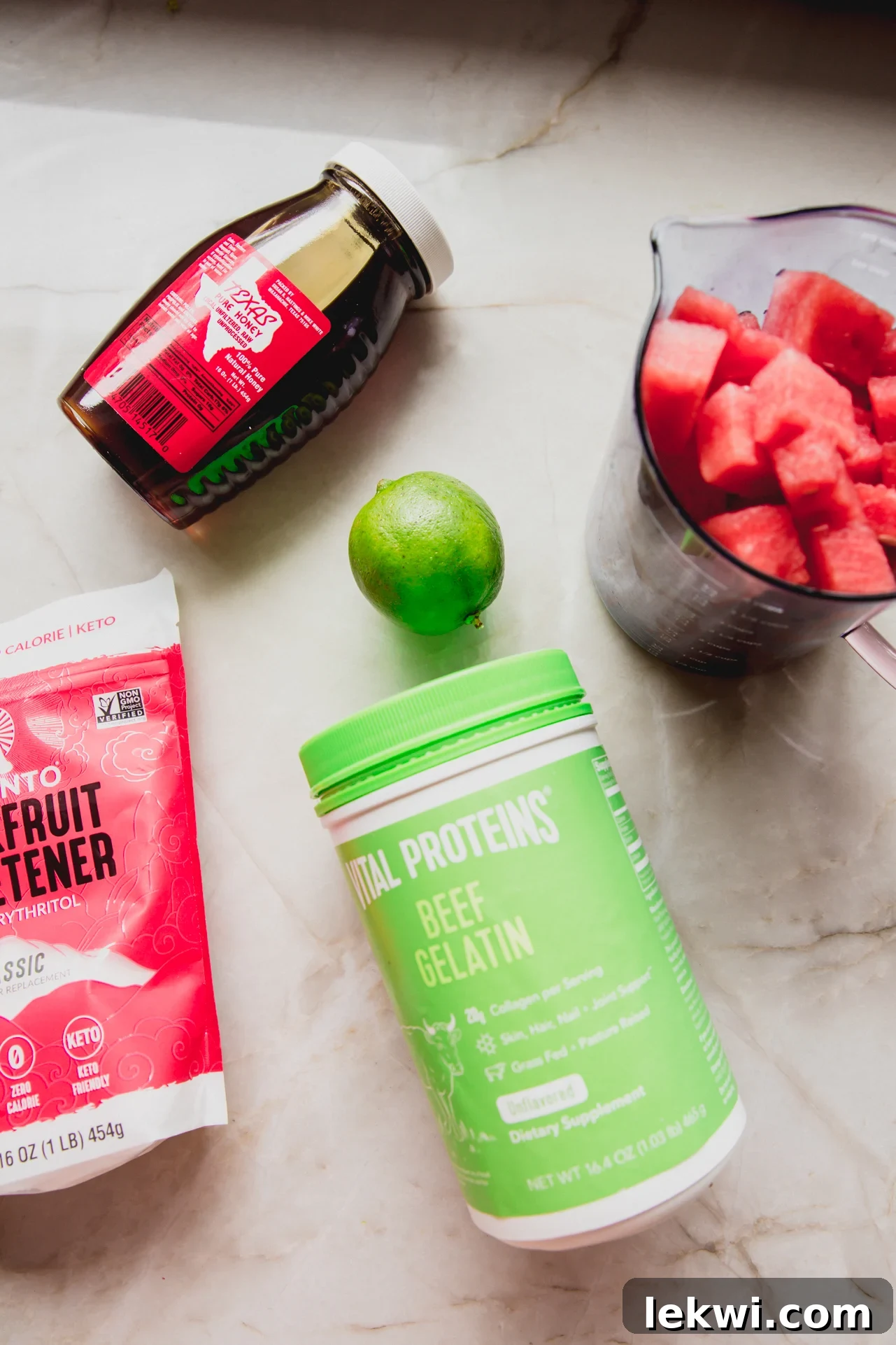 A visual display of the key ingredients required to make sour watermelon gummies, including fresh watermelon chunks, lime, honey, vanilla extract, and gelatin powder.