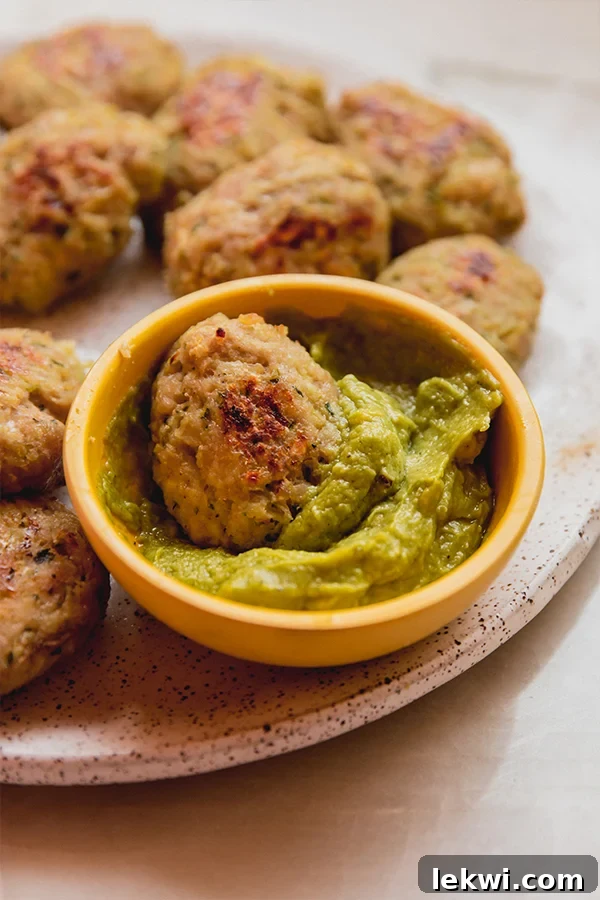 A visually appealing plate featuring a generous serving of crispy zucchini chicken nuggets alongside a vibrant green bowl of guacamole. The nuggets are golden and inviting, perfect for dipping, highlighting the dish's delicious and healthy components.